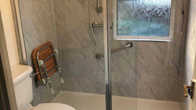 modern walk in shower with wooden foldable shower seat