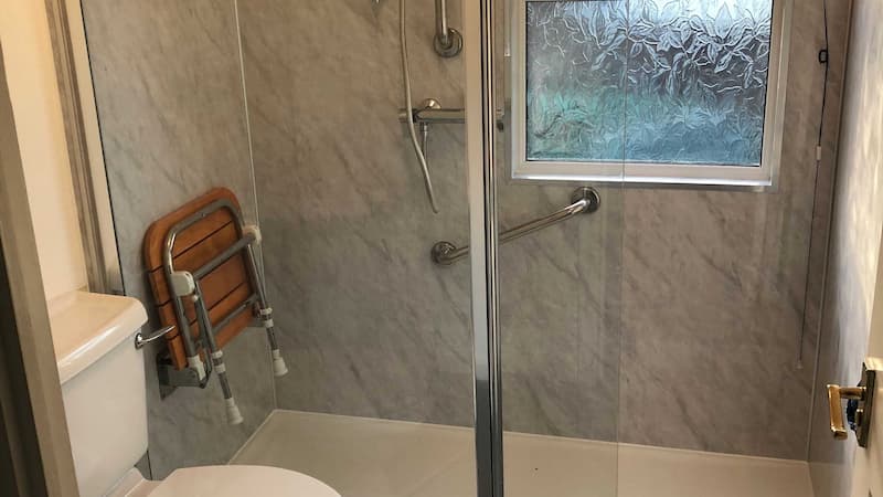 modern walk in shower with wooden foldable shower seat