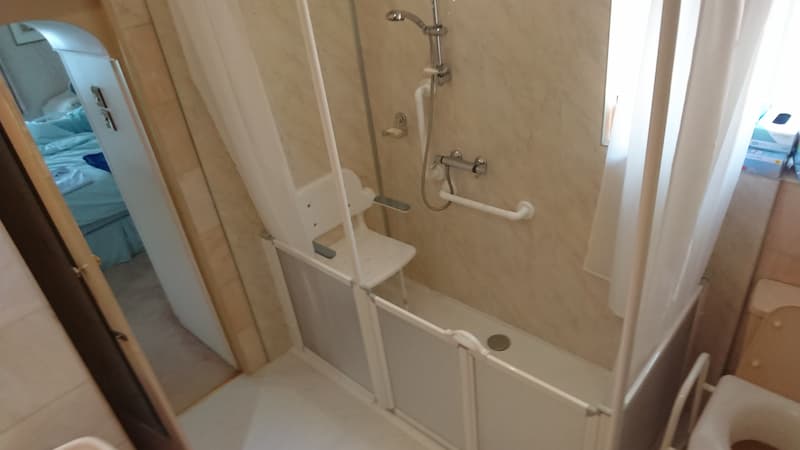 white shower seat in shower with white handle