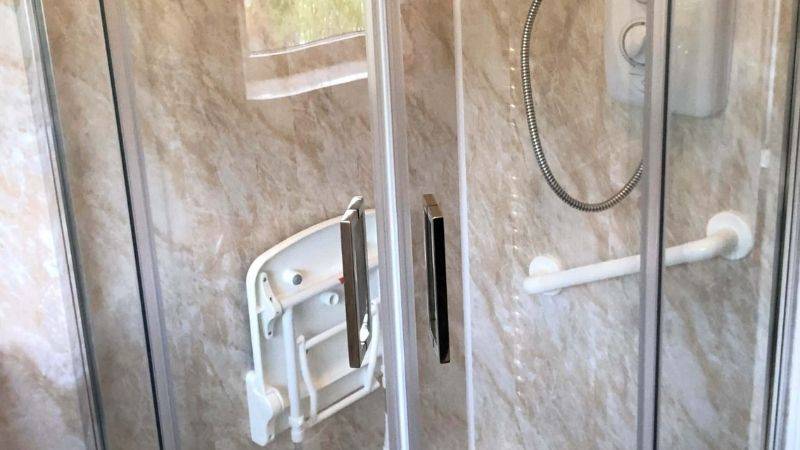 foldable shower seat on side of shower close up